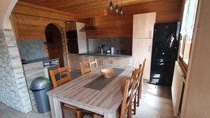 Ett rymligt kök med träskåp, ett stort matbord och en vägg av sten.