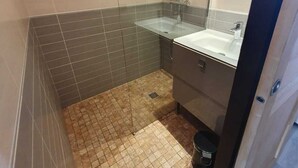 Ett litet badrum med kakel på väggarna, utrustat med dusch, handfat och toalett.