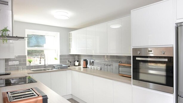 A modern kitchen with white cabinets, stainless steel appliances, and a large window providing natural light. - Spacious home with 8 beds, perfect for work trips or family stays. Enjoy the comfort of free parking, fast Wi-Fi, and a fully equipped space to relax or get things done. (Southampton)