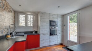 Une cuisine moderne avec un îlot central rouge, un four à micro-ondes et un four encastré dans les meubles de rangement.