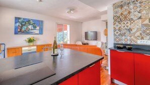 Une cuisine moderne dotée d’un îlot central, de meubles de couleur rouge et d’un crédence décorée.