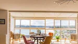 Uma sala de jantar com ampla vista pela janela, uma mesa redonda e cadeiras modernas.