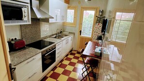 A compact kitchen with white cabinets, a microwave, a stove, and a checkered floor. - Girona Centre 7pax Aparcamiento Coche,moto,bicicleta (Girona)