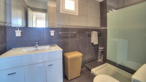 Ein modernes Badezimmer mit großem Spiegel, Waschbecken, Toilette und Duschbereich.