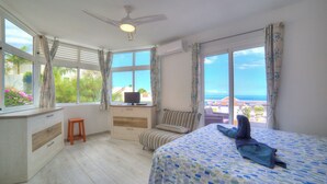 Ein Schlafzimmer mit Bett, Schreibtisch und Meerblick.