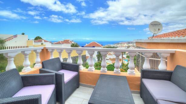 Ein Balkon mit Korbmöbeln und Meerblick.
