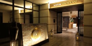 A spa entrance with a reception desk, a large illuminated wall feature, and a sign reading "SPA SOLANI". - KAJIMACHINOYU SPA SOLANI (Hamamatsu)