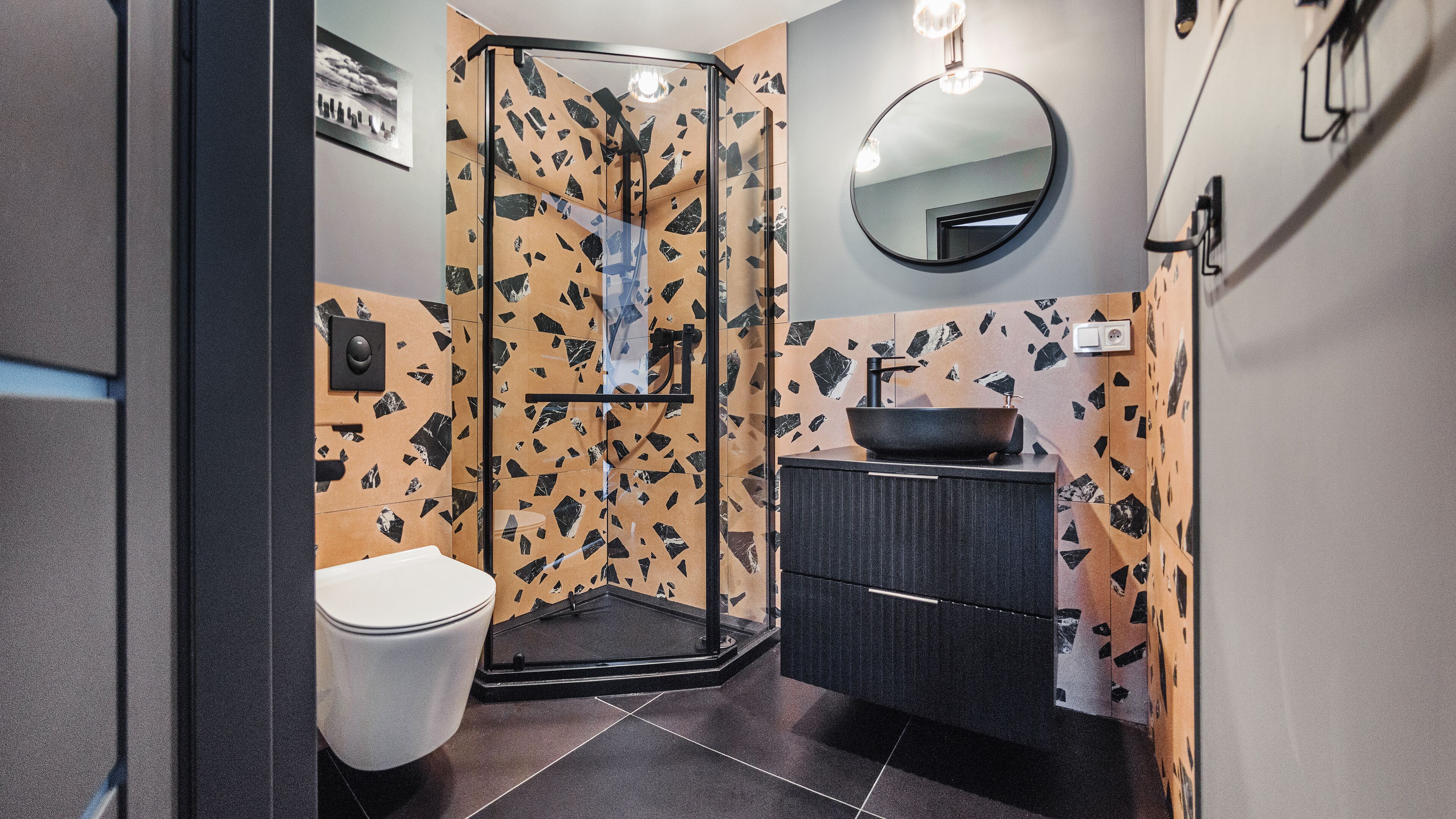 Et moderne badeværelse med brusekabine i glas, en vask med skål og et toilet.