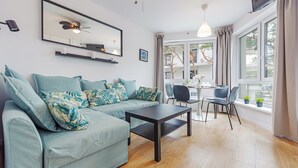 A modern living room with a sofa, a coffee table, and a dining area with chairs and a table. - Apartamenty Sun & Snow Wypoczynkowa (Ustka)