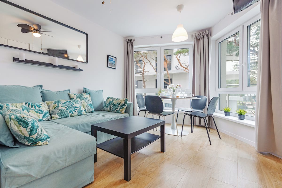 A modern living room with a sofa, a coffee table, and a dining area with chairs and a table.