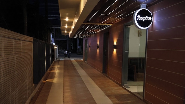 A corridor with a reception area, a scooter parked outside, and a brick wall on one side. - Hotel Grand Zuri (Agartala)