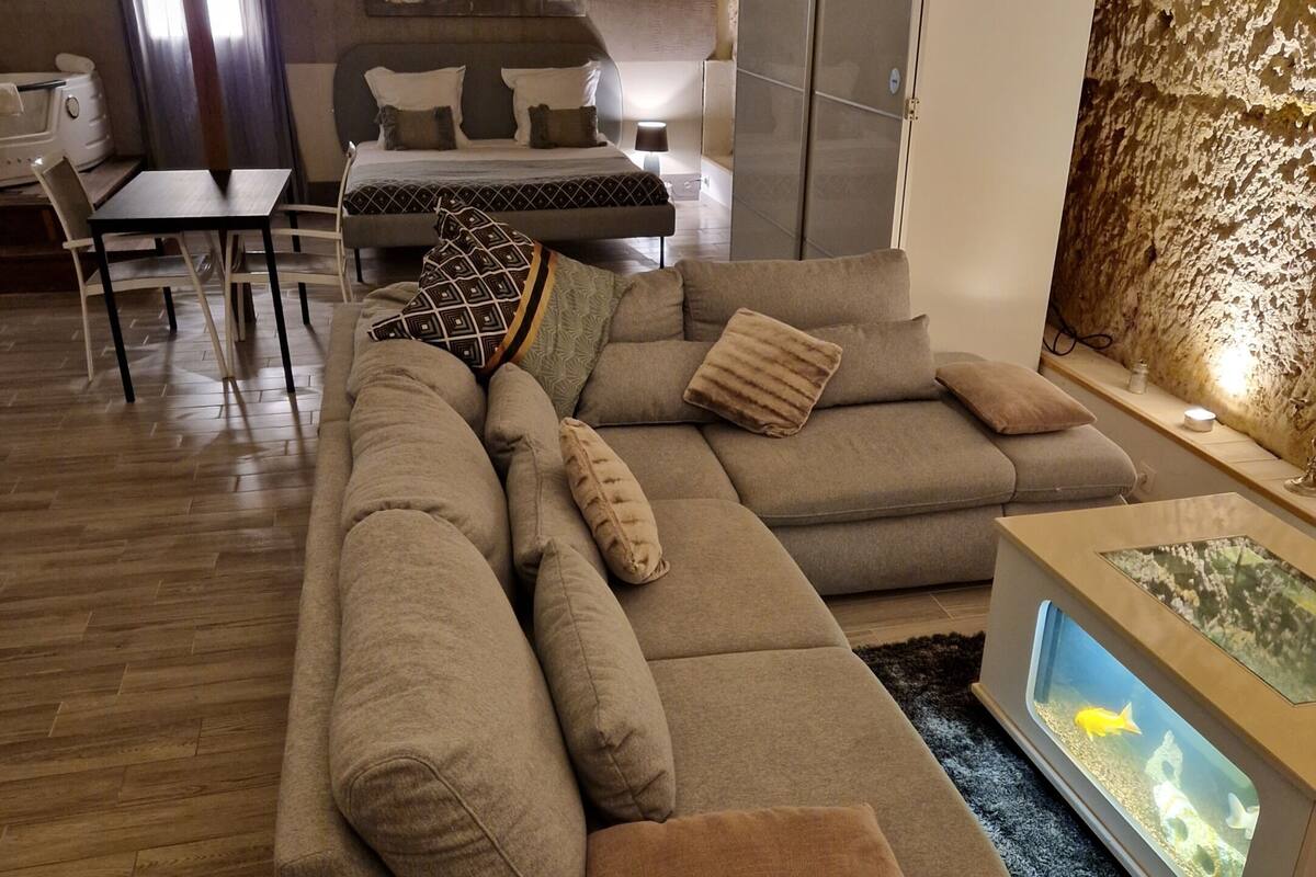 A modern living room with a sectional sofa, a dining area, and a fish tank.