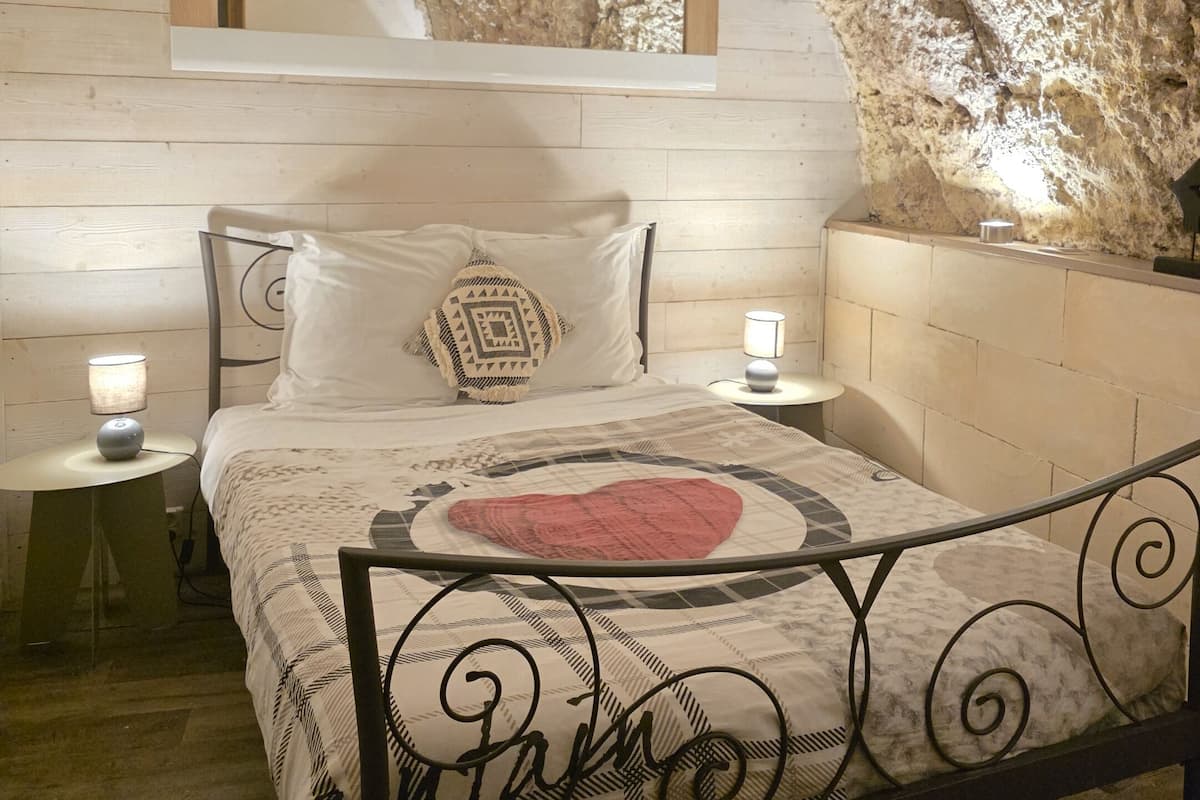 A bedroom with a bed, nightstands, and a unique rock wall.