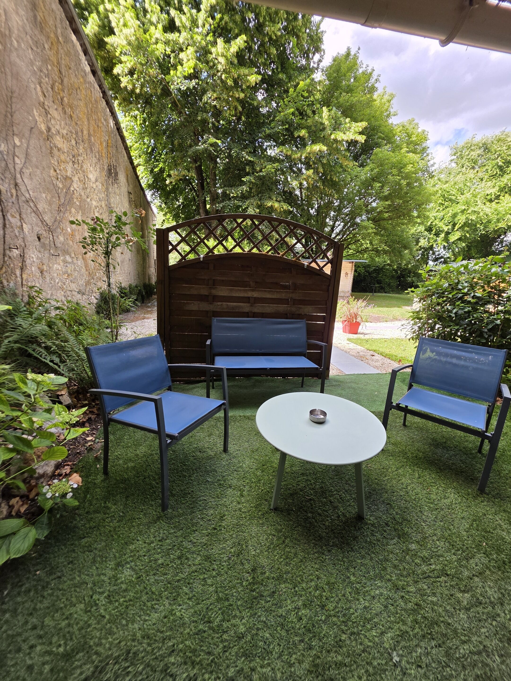 A patio with a wooden bench, two chairs, and a small table.