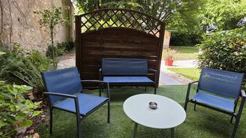 A patio with a wooden bench, two chairs, and a small table.
