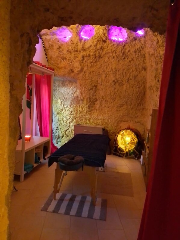 Una habitación con una cama, una mesita, una estantería y una pared con textura.