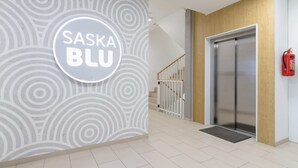 Un interior moderno con un letrero circular que dice "SASKA BLU", una escalera y un extintor.