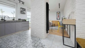 Une cuisine moderne avec un mur en briques blanches, des meubles de couleur grise et des carreaux de sol à motifs.