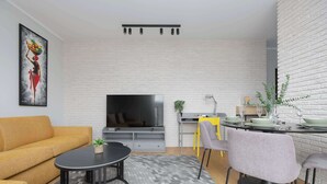 Un salon moderne comprenant un canapé, une table basse ronde, un téléviseur à écran plat et un coin repas avec des chaises et une table.