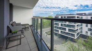 Un balcon avec un canapé, une petite table et des plantes en pot.