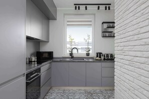Una cocina moderna con gabinetes grises, un microondas negro y una ventana con vistas a edificios.