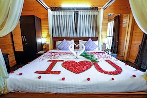 Uma cama decorada com um arranjo de flores vermelhas em formato de coração que escreve 'I LOVE YOU' e dois cisnes feitos de flores.