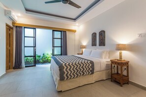 Relax in this inviting room with a large bed, ceiling fan, and two wall-mounted lamps.