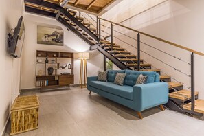 Relax in this stylish living room with a sofa, bookshelf, and staircase.