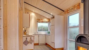 Une cuisine de taille réduite avec des murs en bois, une fenêtre et un poêle à bois.