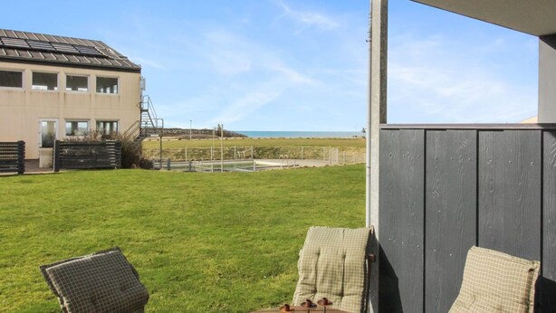 A patio with two chairs and a table, overlooking a grassy area with a building in the background. - "Tinke" - 150m from the sea by Interhome (Løkken)