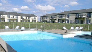 A swimming pool with lounge chairs and a fenced area, surrounded by modern apartment buildings. - "Tinke" - 150m from the sea by Interhome (Løkken)