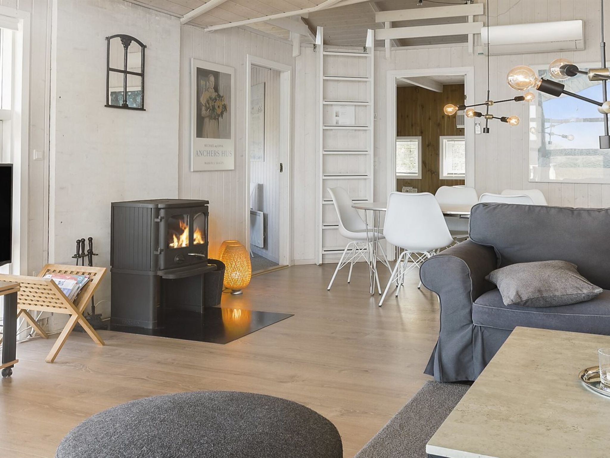 Uma sala de estar moderna com lareira a lenha, móveis brancos e um ambiente acolhedor.