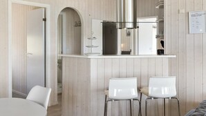 Una cocina moderna con una isla central, sillas blancas y detalles de madera.