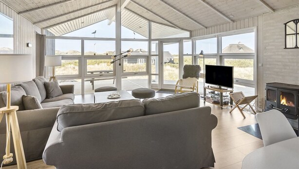Un salón amplio con techos altos, ventanas grandes, chimenea y zona de estar acogedora.
