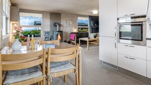 Une cuisine chaleureuse équipée d’une cuisinière, d’un four et d’un coin repas avec des chaises et une table.