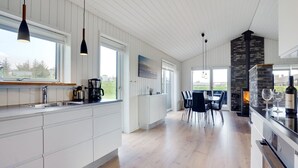 Eine moderne Küche mit weißen Schränken, einer zentralen Kochinsel und einem Essbereich mit Tisch und Stühlen.
