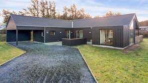 Ein modernes, zweistöckiges Gebäude mit geneigtem Dach, großen Fenstern und einer Schotterauffahrt.