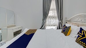 A hotel room with a bed, a desk, and a window with curtains. - Hotel O Teguh Homestay Syariah (Pekanbaru)