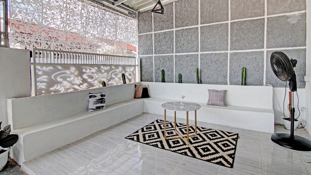 A modern interior with a white sofa, patterned rug, and decorative cacti. - Hotel O Teguh Homestay Syariah (Pekanbaru)