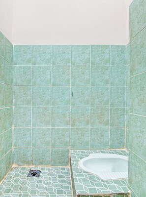 A bathroom with a freestanding bathtub, a shower area, and a tiled floor. - Hotel O Teguh Homestay Syariah (Pekanbaru)