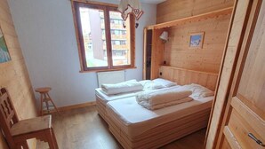 Una stanza piccola in legno con un letto, una sedia e una finestra.