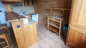 Una cucina rustica con mobili in legno, un lavandino piccolo e un pavimento piastrellato.