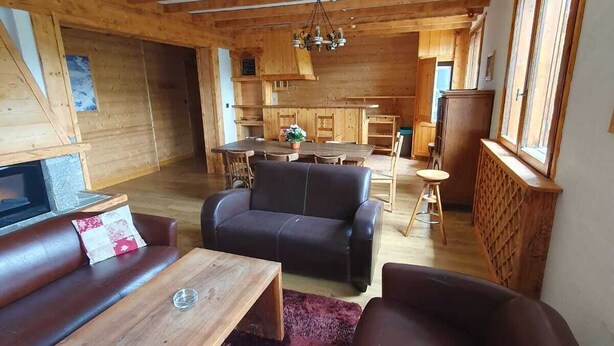 Un accogliente soggiorno con travi in legno, un divano, un tavolino e un camino.