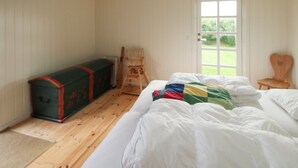 Ein Schlafzimmer mit Bett, Kommode, Stuhl und Fenster.