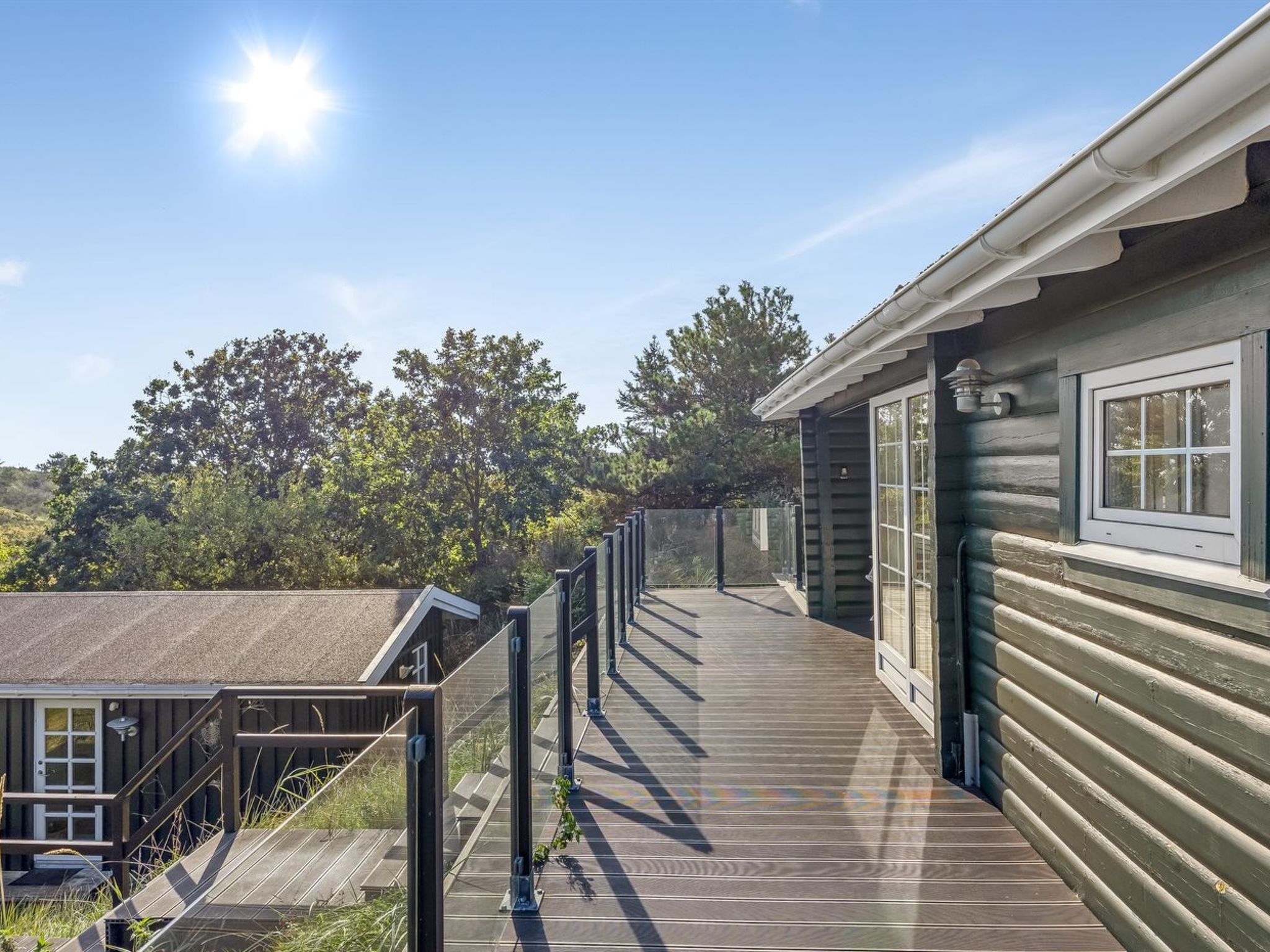 A wooden deck leading to a cabin with a window and a door, surrounded by trees.