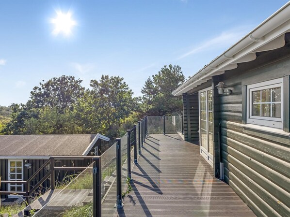 A wooden deck leading to a cabin with a window and a door, surrounded by trees.