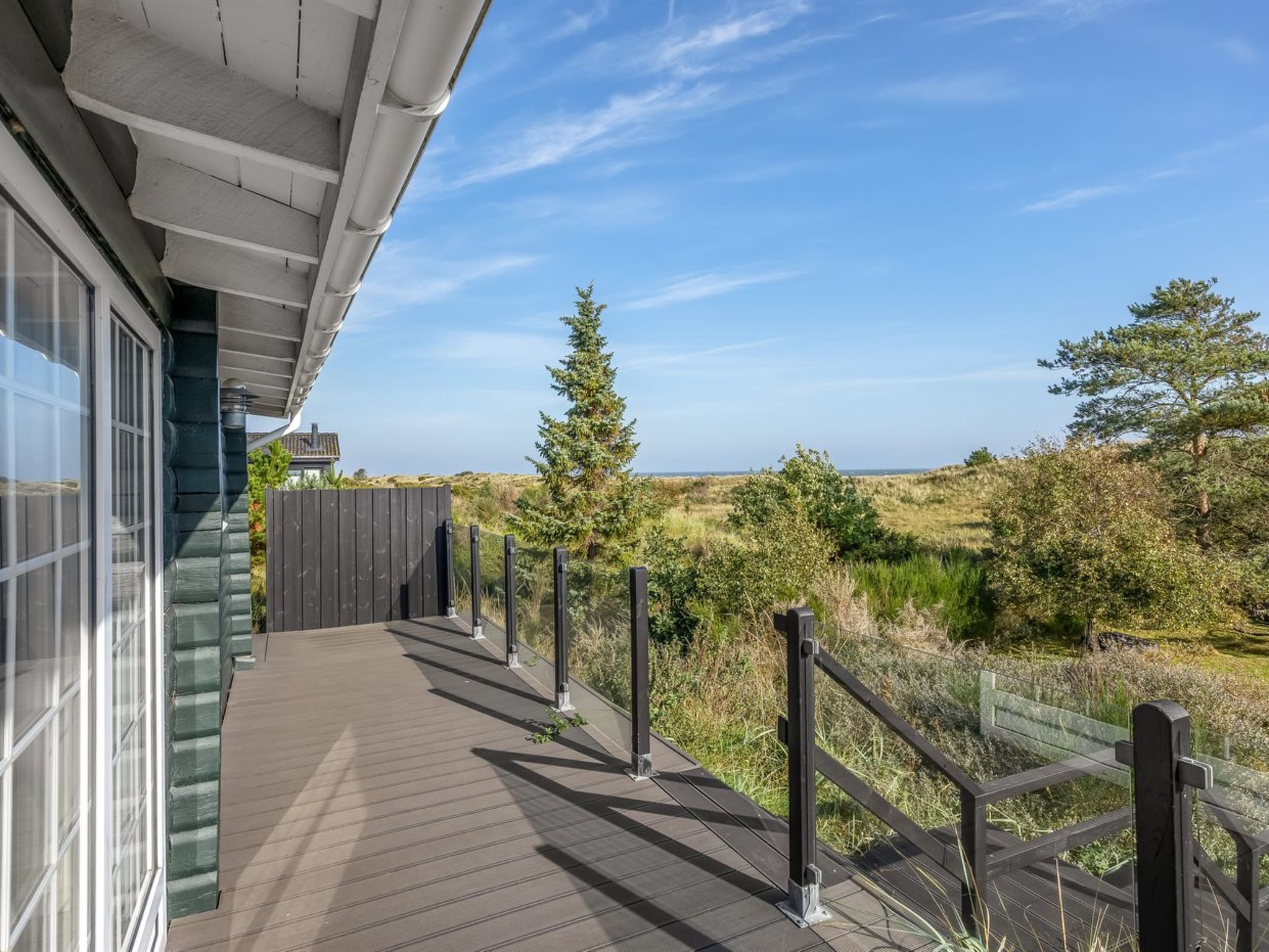 A wooden deck with a railing overlooking a natural landscape.