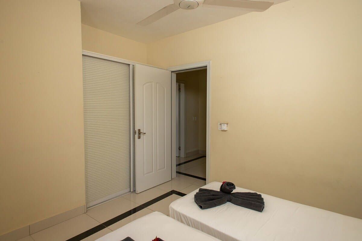 Een hotelkamer met een bed, een gesloten deur en een plafondventilator.