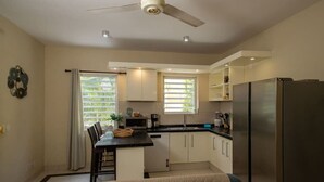 A compact kitchen with a dining area, a ceiling fan, and a refrigerator. - Trupial C3 Relax & Dive Resort Bonaire Village (Kralendijk)