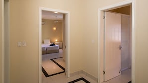 A hallway with a bed in the background, a closed door, and a tiled floor. - Trupial D3 Relax & Dive Resort Bonaire Village (Kralendijk)